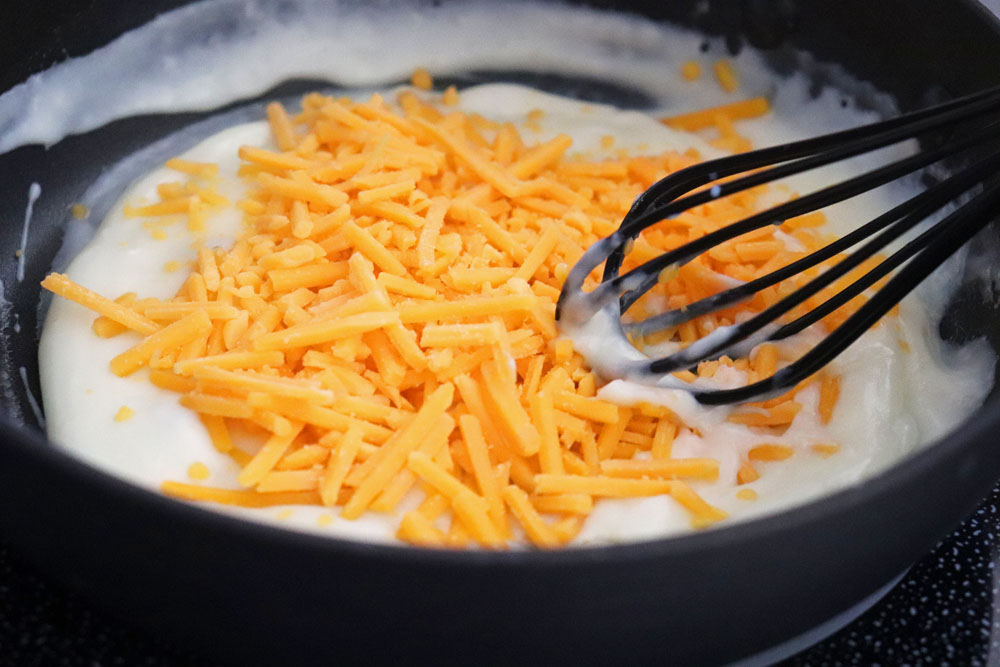 Adding shredded cheddar to the sauce