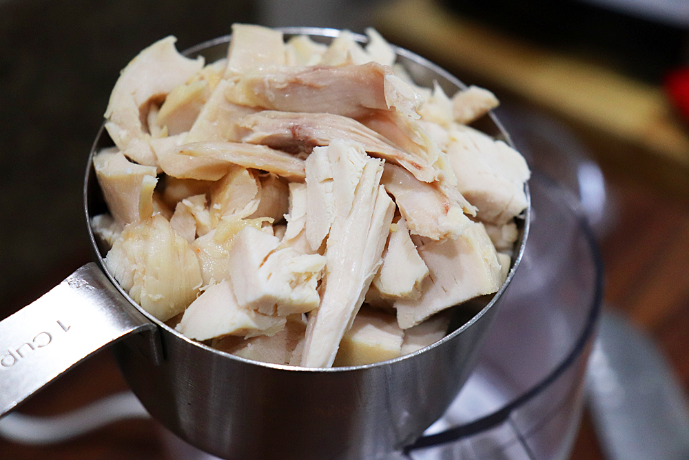 Pulled rotisserie chicken in a stainless measuring cup