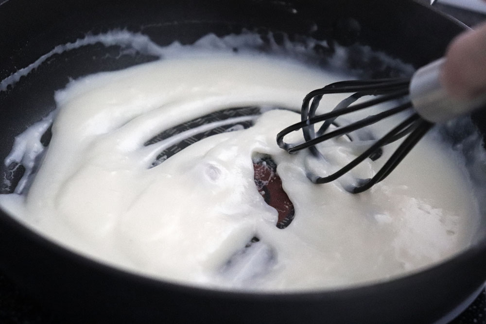 Whisking the white sauce until smooth