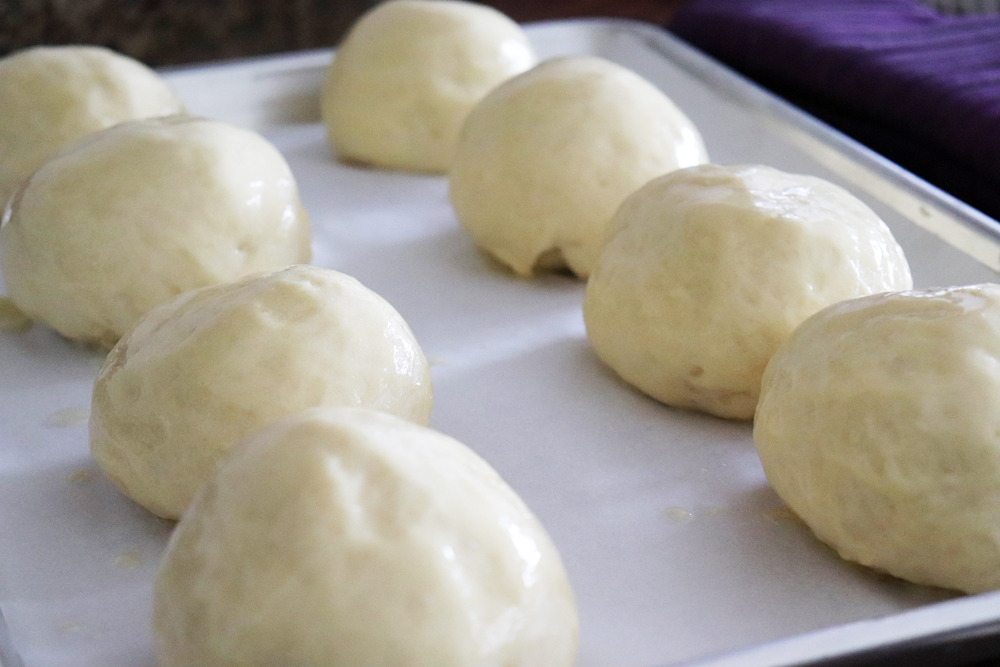 Risen dough balls buttered and ready to bake